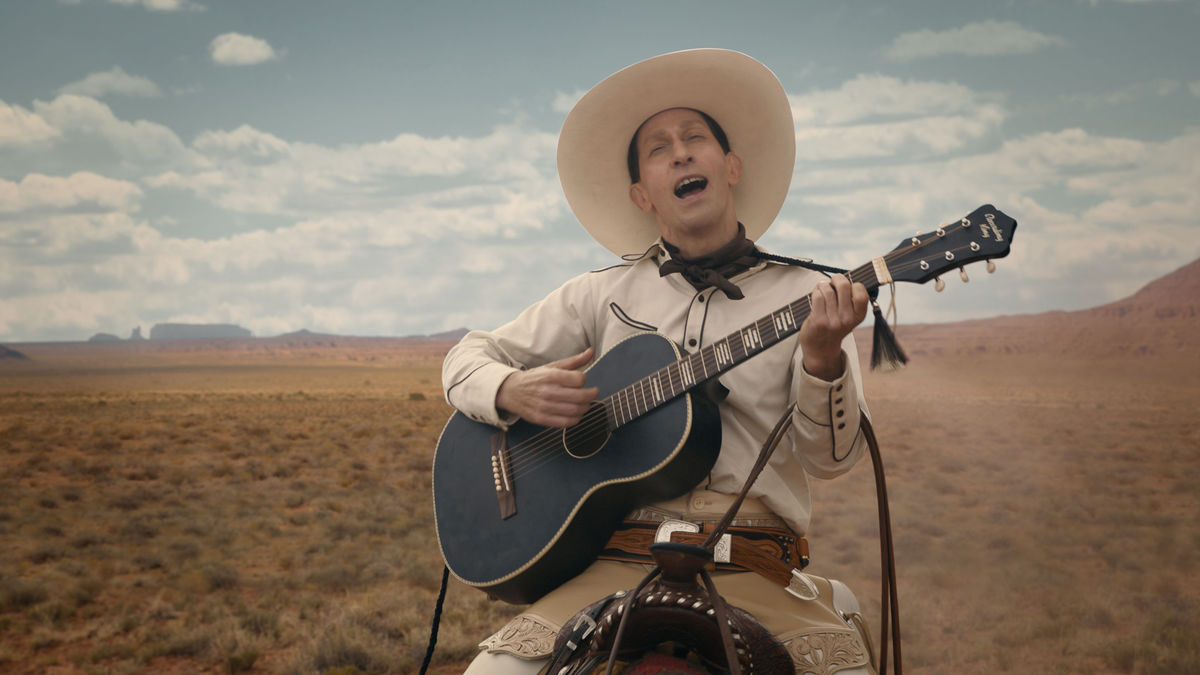 Buster Scruggs, a dandy gunslinger, playing the guitar on horseback.